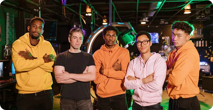 Profesjonalna drużyna e-sportowa stoi razem na arenie gier, ubrana w jednakowe stroje i pewnie pozująca w świetle neonów.